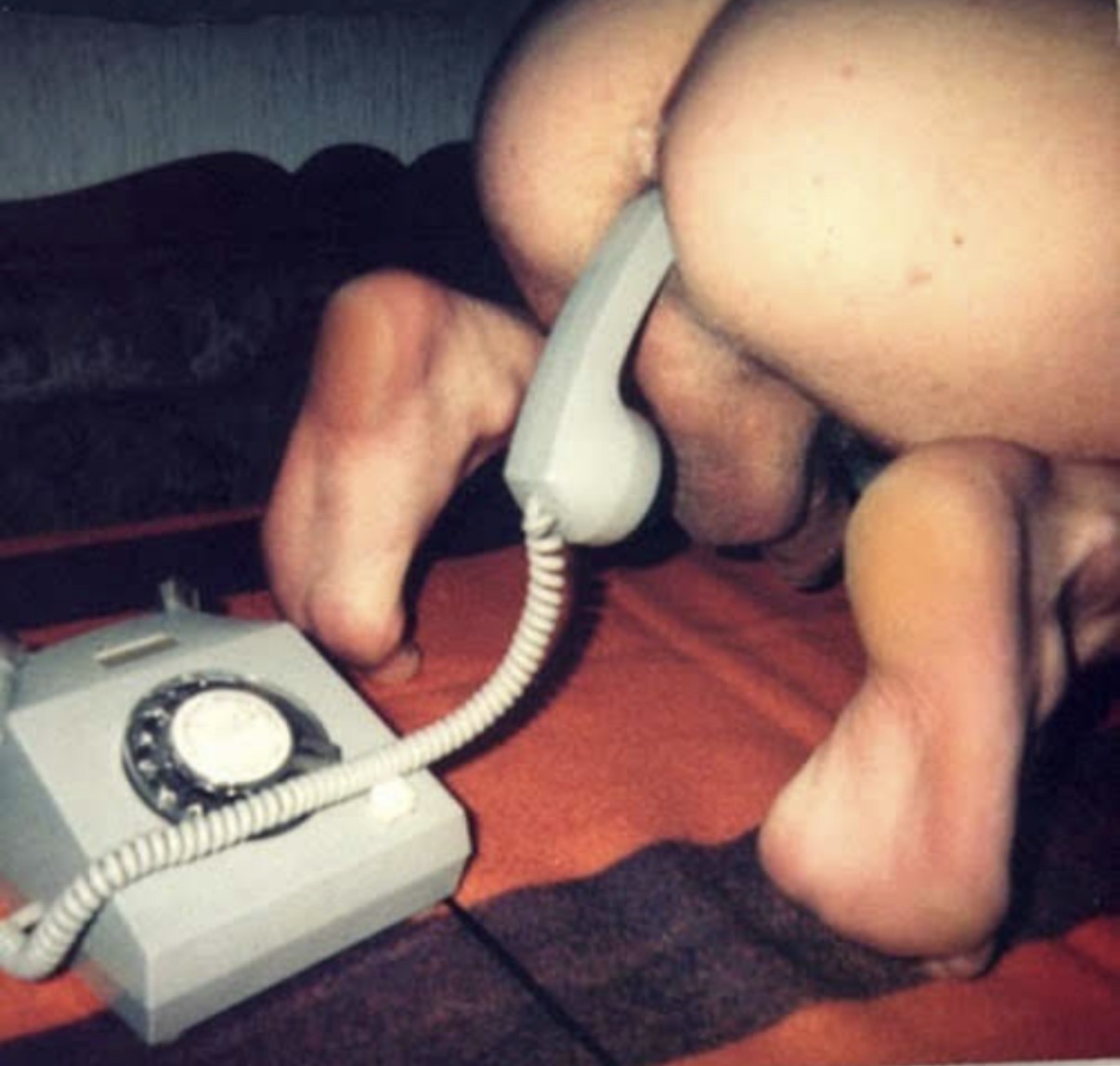 Hand holding a telephone receiver above a rotary phone