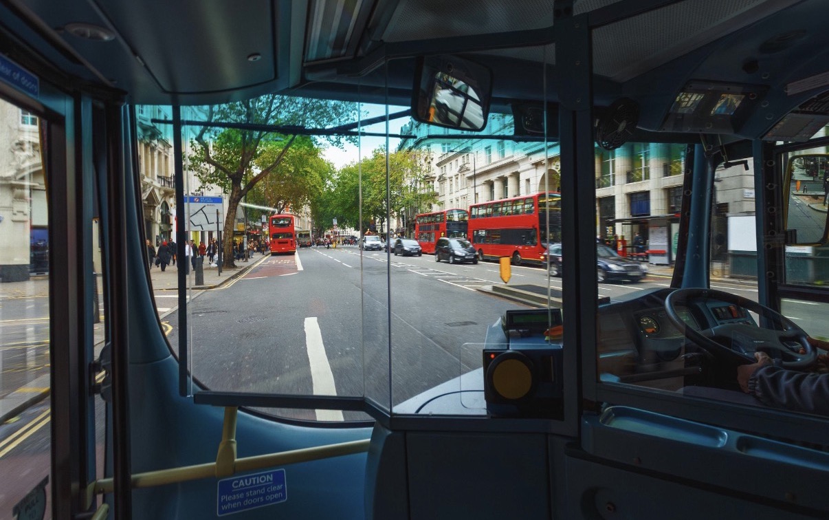 View from inside a London bus showing the driver area and road ahead