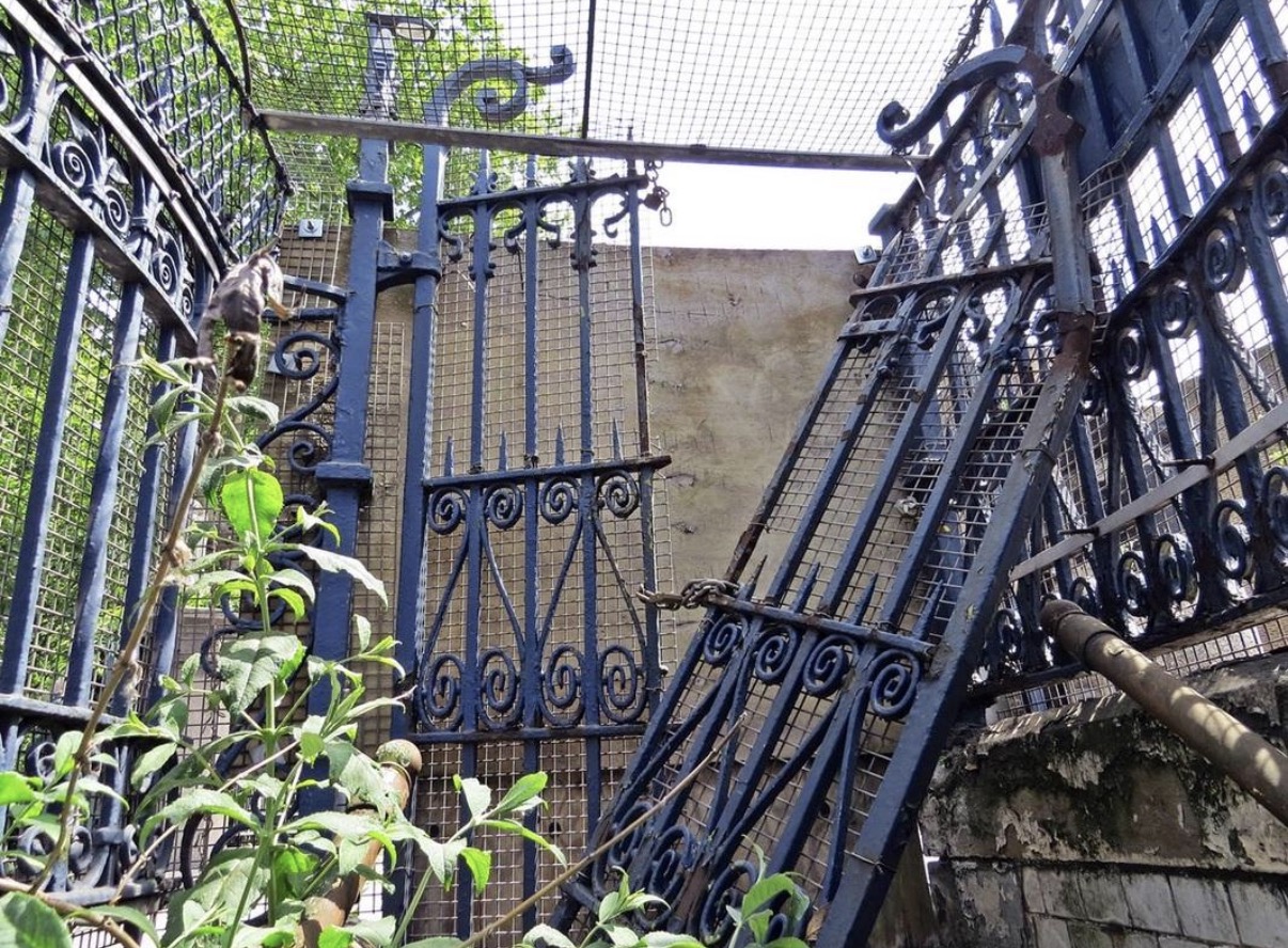 Overgrown gated entrance to a former underground public toilet