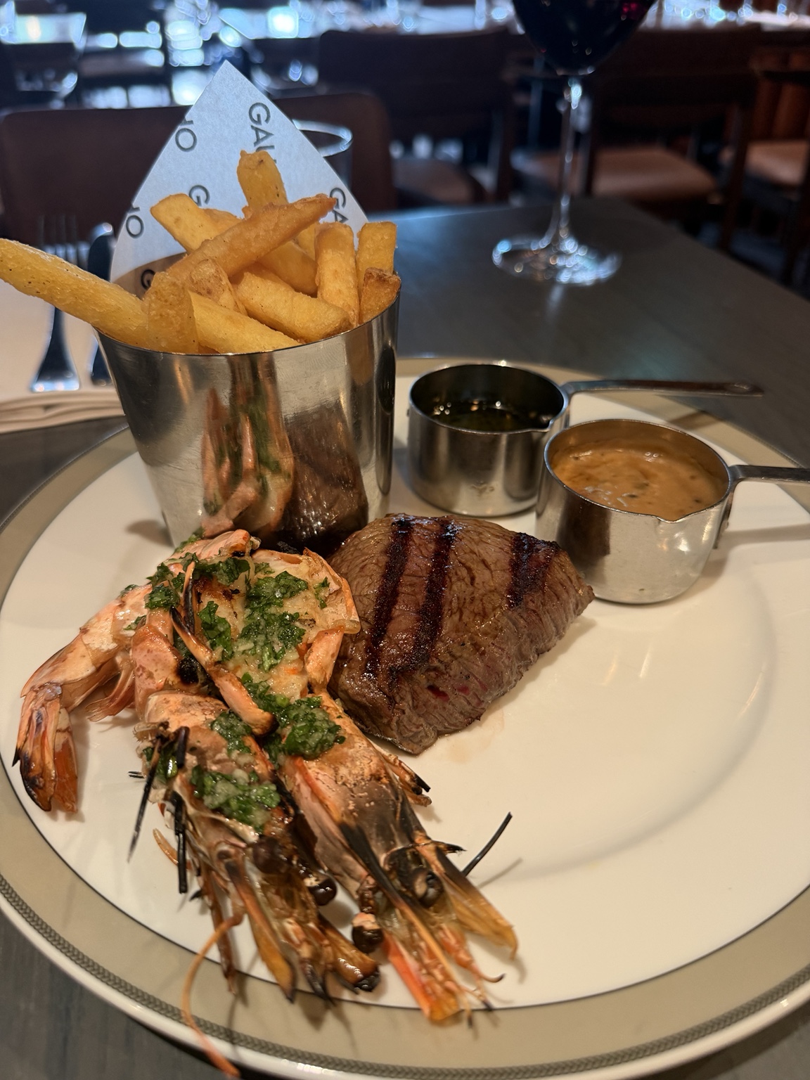 A Gaucho lunch plate with a 160 gram steak, grilled prawns, chips and two sauces